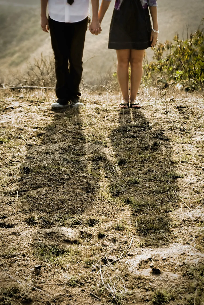 Holding hands on a backlit hillside