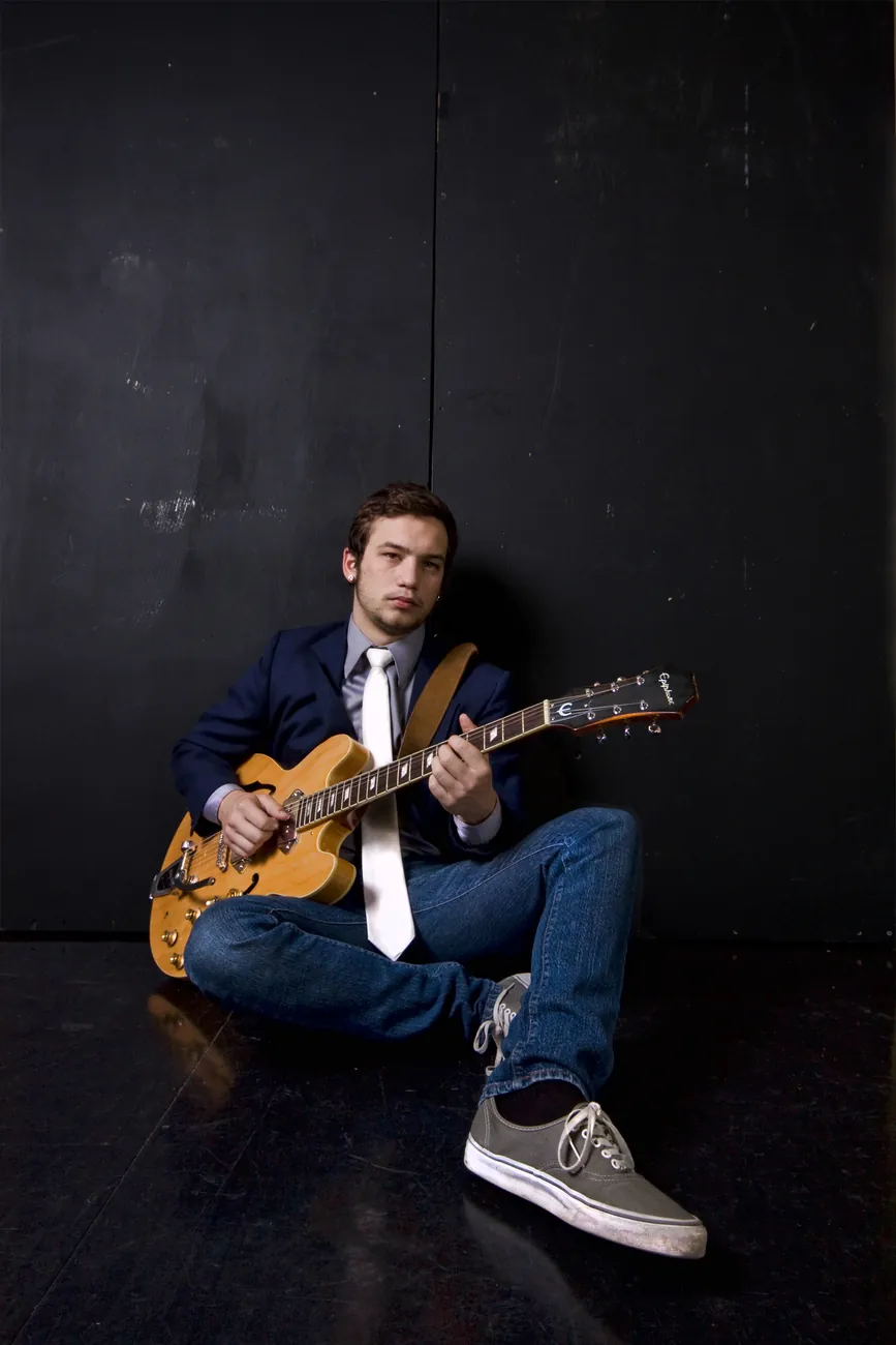 Seated with a hollow-body guitar