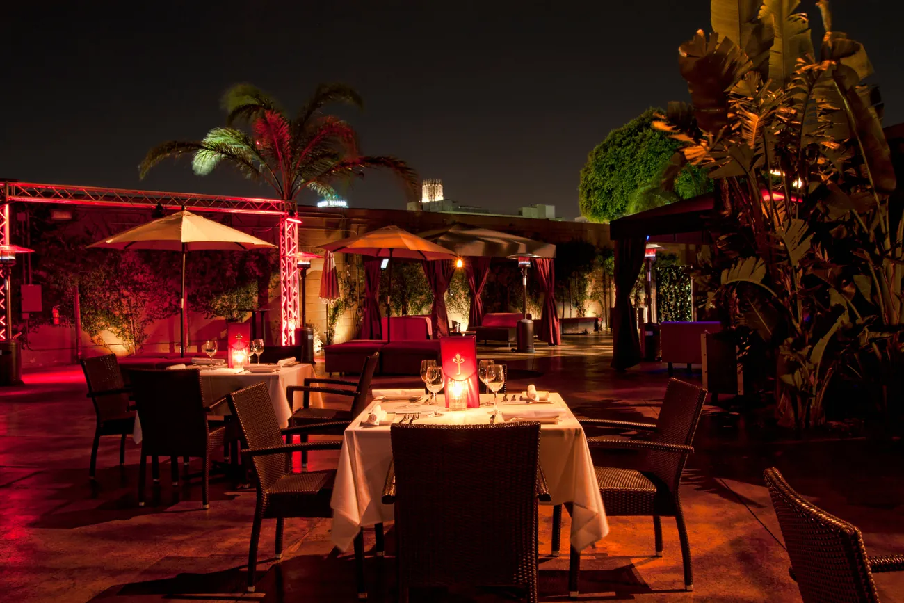 Red-lit patio with umbrellas and palms